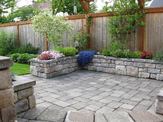 nice-patio-area-with-garden-andnice-wood-wall-on-the-border-and-lifted-flowers-on-stone-wall